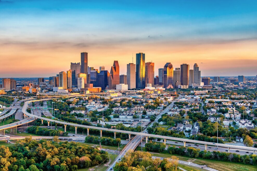 The Houston skyline illuminated by warm sunrise light, representing Avionn Automotive’s emergence from its hometown into national visibility.